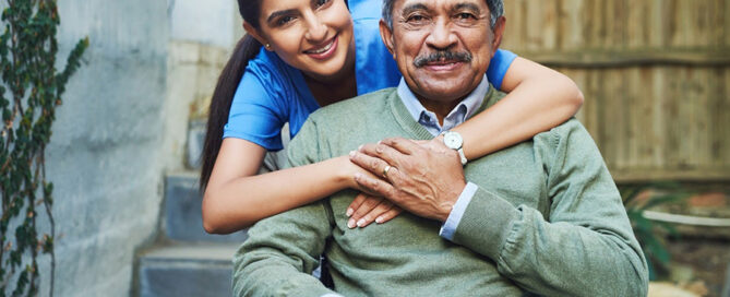 A female caregiver hugs a senior man in a wheelchair, exemplifying caring for elderly parents