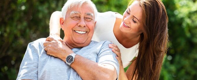A smiling elderly man outdoors with a caregiver, illustrating a caring environment, the key to what to look for in a senior living community