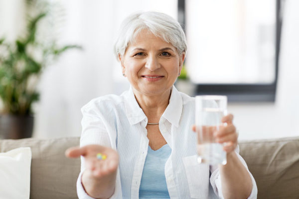 Adult lady drinking her daily supplements of vitamins and minerals.
