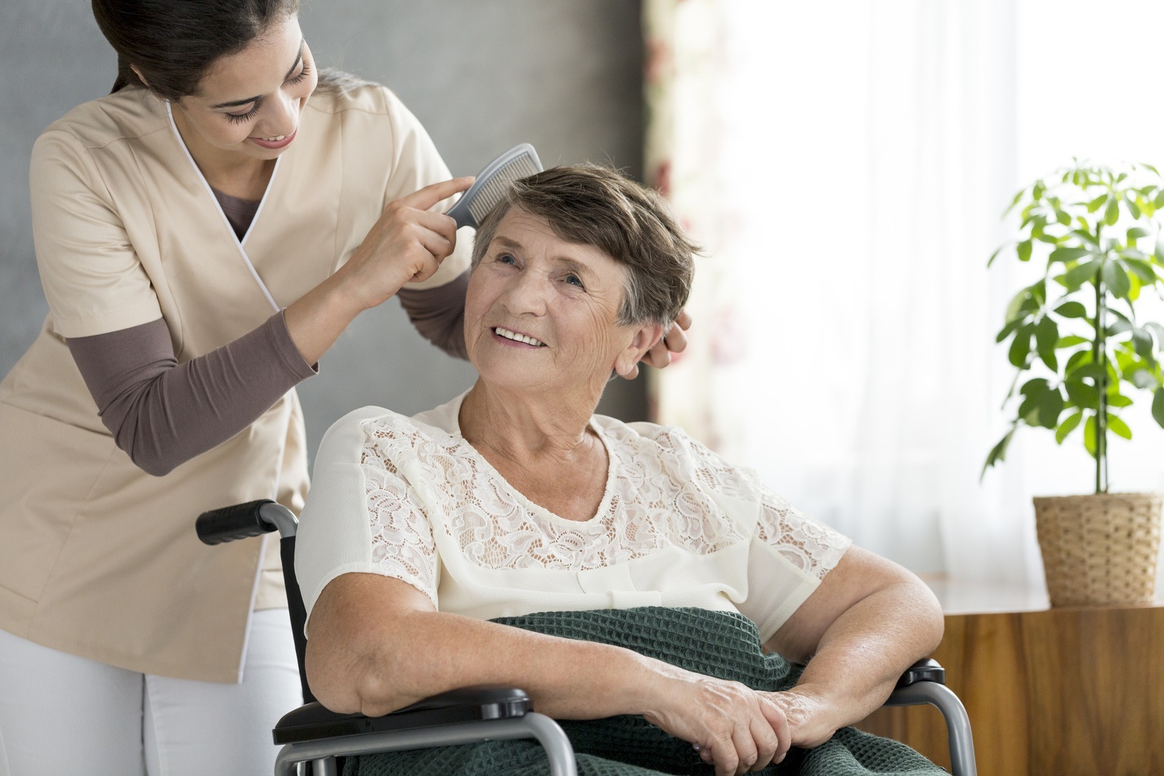 Care giver combing senior woman's hair.