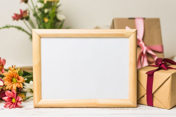 Close up blank wooden frame with gift flowers