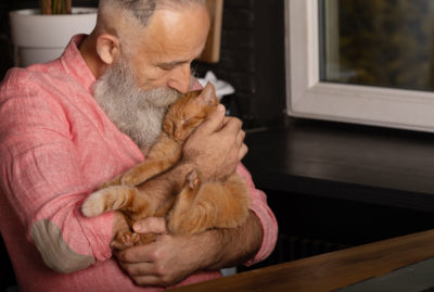 Retired man cuddling a cat 