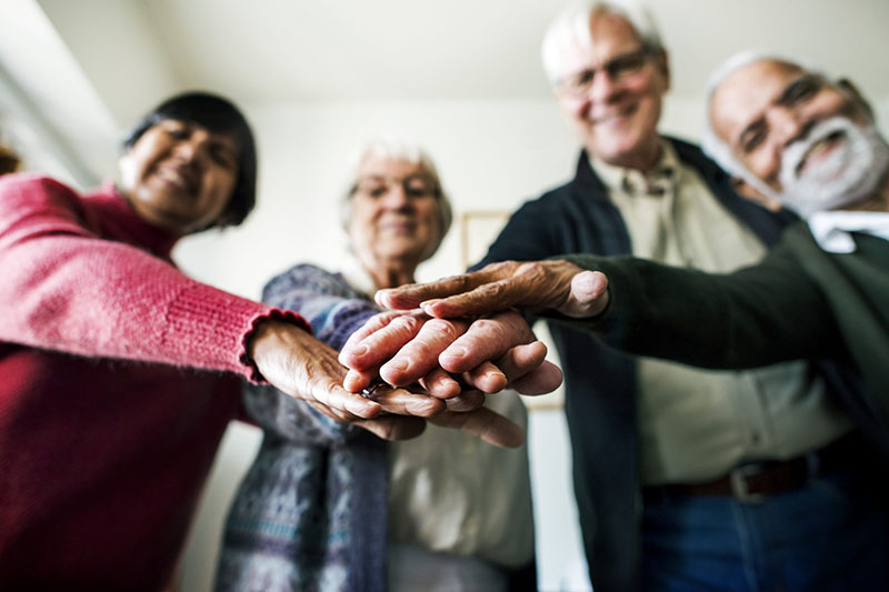 Group of senior adults hands together representing the resident council. how to prepare for a retirement community