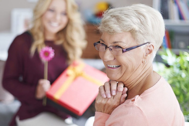 Happy senior about to receive a gift concept image for gift ideas for retired women.