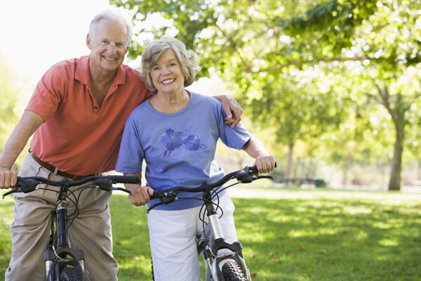 Senior couple joyfully riding bikes, experiencing the benefits of retirement communities with a maintenance-free lifestyle