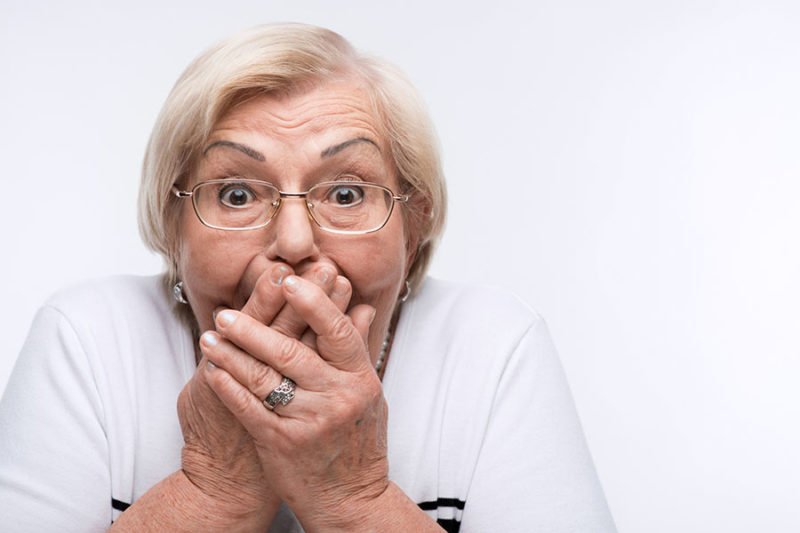 senior woman covering her mouth concept image for speech problems in the elderly.