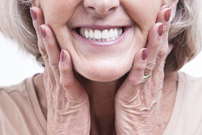 Senior woman wearing new dentures concept image for how long does it take to get used to dentures. Adult woman searching for the best part time jobs for retirees.