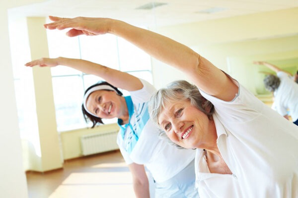 Seniors participating in stretching exercises, highlighting the benefits of staying active and healthy in a lifecare community 