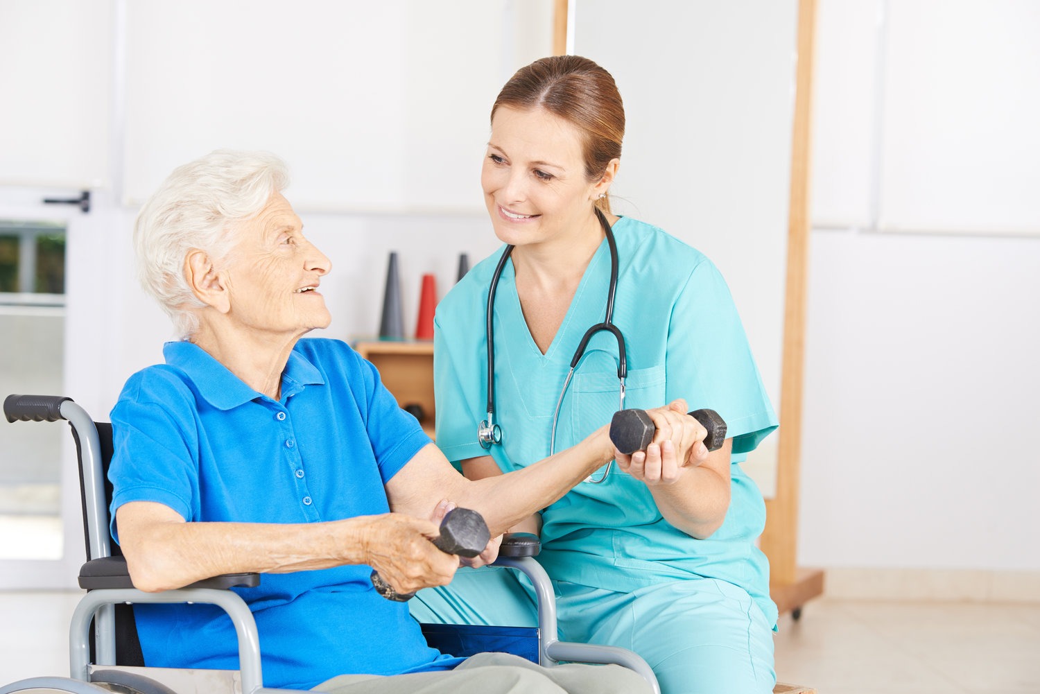 Skilled nurse helping elderly lady with her physical therapy.