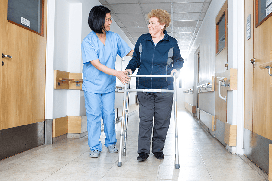 Staff assisting a senior woman with walking exercises during a physical therapy session