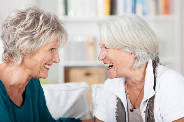 Two happy woman enjoy a laugh together at a CCRC