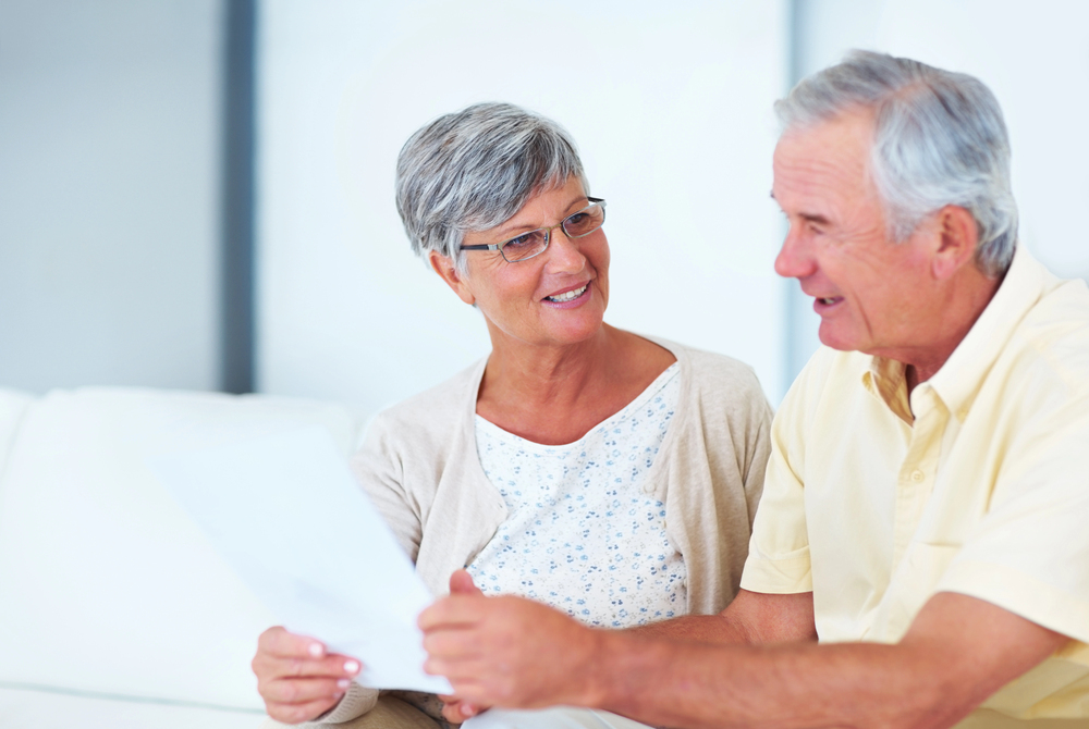 senior couple reviewing documents together at home and discussing the benefits of early retirement planning for their future security