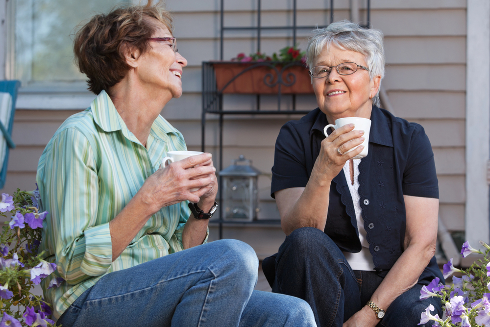 How Much Does A Life Plan Community Cost In Pennsylvania? 1 two older women enjoying coffee together on a porch, featured in life plan community cost information.