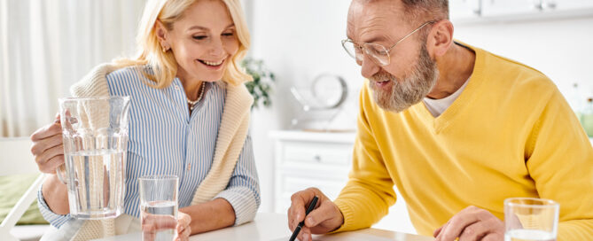 How To Make A Mid-Year Retirement Planning Check-In More Productive 1 an older couple smiling while reviewing documents with a calculator. this highlights a mid-year retirement-planning session at home.