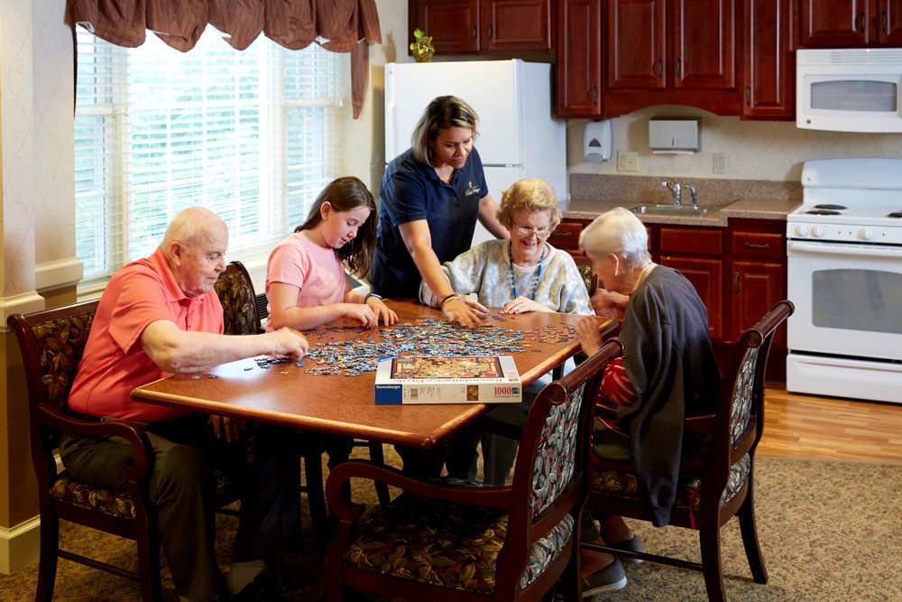 Care providers working closely with older adults with companion care & completing a puzzle