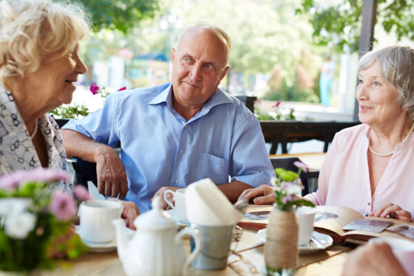 seniors enjoying coffee and conversation outdoors as part of a vibrant senior community care environment