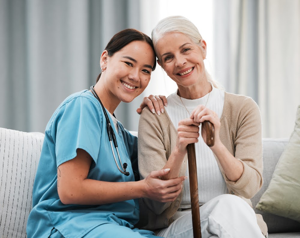 a nurse smiling beside a senior woman holding a cane, representing compassionate senior memory care