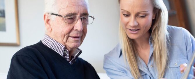 Ccrc Meaning: What Does Ccrc Stand For? 8 senior man reviewing information with caregiver, illustrating the question what does ccrc mean in retirement planning